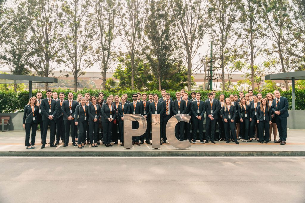 Groepsfoto van hospitality studenten in pak voor het Philips Innovation Campus-logo, symbool voor ambitie en toekomstgericht onderwijs bij EuroCollege.