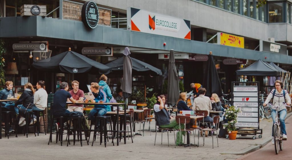 Studenten en bezoekers genieten van de levendige sfeer op het terras voor EuroCollege Rotterdam, gelegen is het hart van de stad.